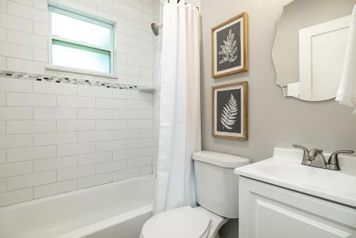 Un baño blanco con inodoro y lavabo. en Saint Pete Hideaway Cozy Urban Escape Oasis, en San Petersburgo