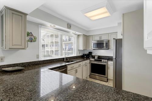 a kitchen with white cabinets and a black counter top at Seagrove 11D by Wild Dunes, Oceanfront Condo in Isle of Palms
