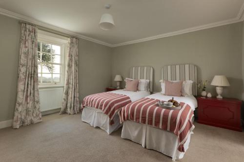 a bedroom with two beds and a window at New Ladykirk Farmhouse in Ladykirk