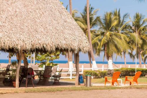 un grupo de sillas y mesas en una playa con palmeras en Hotel & Villas Tangerí, en Jacó