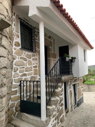 a stone house with a balcony and a staircase at Casa da Fonte in Mangualde