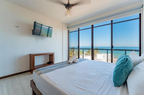 a bedroom with a large bed with a view of the ocean at Condo vista al mar, alberca rooftop Chixchulub in Chicxulub