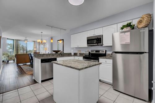 a kitchen with white cabinets and a refrigerator at Shipwatch 110B by Wild Dunes, Ocean View Condo in Isle of Palms
