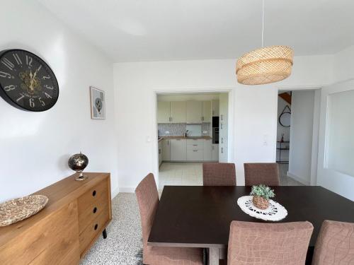 une salle à manger avec une table et une horloge au mur dans l'établissement La Joliette, maison 5 chambres, à Rumegies