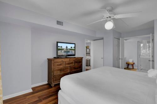 a white bedroom with a bed and a flat screen tv at Shipwatch 110B by Wild Dunes, Ocean View Condo in Isle of Palms