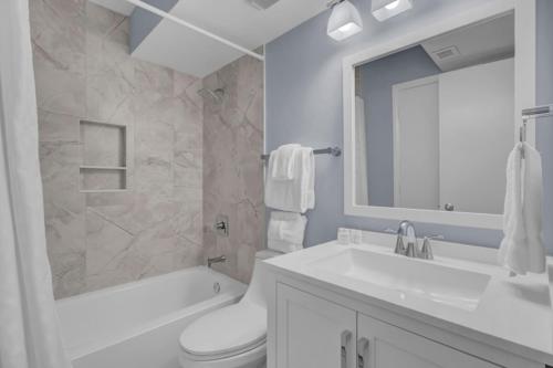 a white bathroom with a sink and a toilet and a tub at Shipwatch 110B by Wild Dunes, Ocean View Condo in Isle of Palms