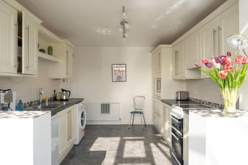 a kitchen with white cabinets and a vase of flowers at Portrush Seaview Beach House in Portrush