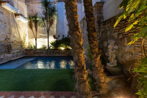 a swimming pool with palm trees in a courtyard at 5 Sentidos - Suites de Lujo in Tudela