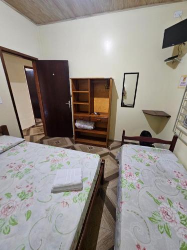 a room with two beds and a cabinet in it at Pousada Amigu's in Pontal do Paraná