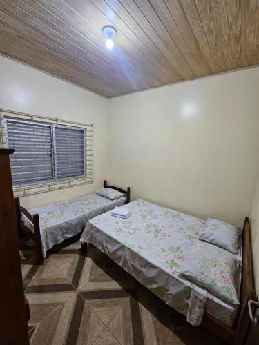 two beds in a room with a window at Pousada Amigu's in Pontal do Paraná