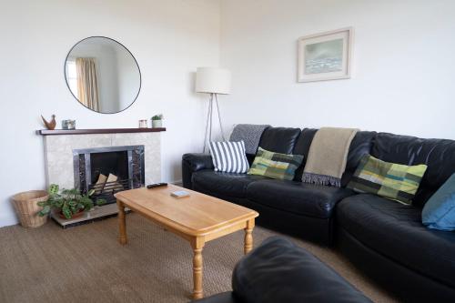 a living room with a black couch and a table at Portrush Seaview Beach House in Portrush