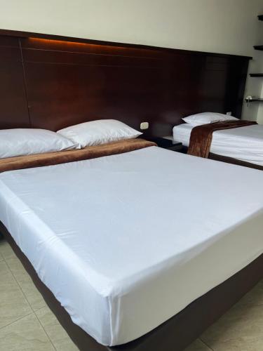 two beds in a room with white sheets at Hotel Marialu in Ocaña