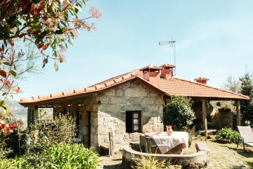 a stone house with a table in front of it at Casa dos Castros in Travassós