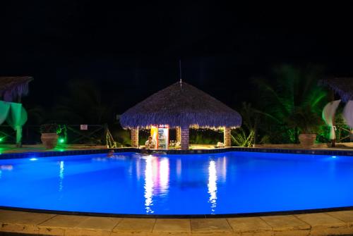 a swimming pool at night with a gazebo at Pousada Aruana in Canoa Quebrada