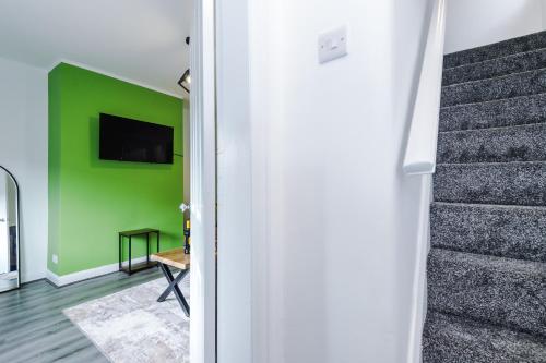 a living room with a green wall and stairs at NEW! The Acacia House Lodge - Modern & Stylish 3 Bed By Parydise Properties Ltd - Ideal for families or business stays! in Shevington