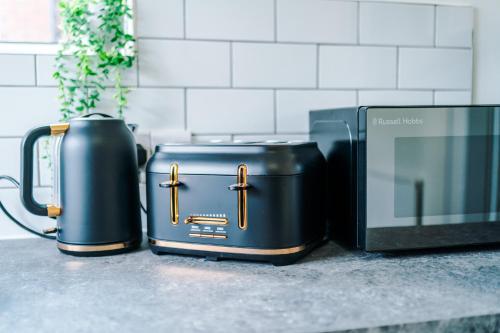 a couple of briefcases next to a microwave at NEW! The Acacia House Lodge - Modern & Stylish 3 Bed By Parydise Properties Ltd - Ideal for families or business stays! in Shevington