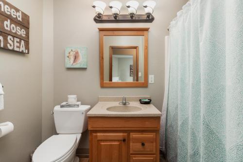 a bathroom with a toilet and a sink and a mirror at Ocean Terrace Condominiums in Lincoln City
