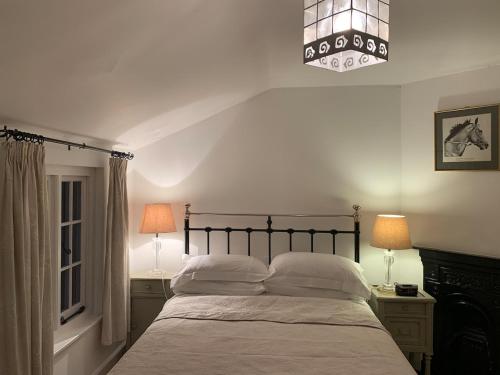 a bedroom with a bed with two night stands and two lamps at Cute cob cottage in Winterborne Stickland