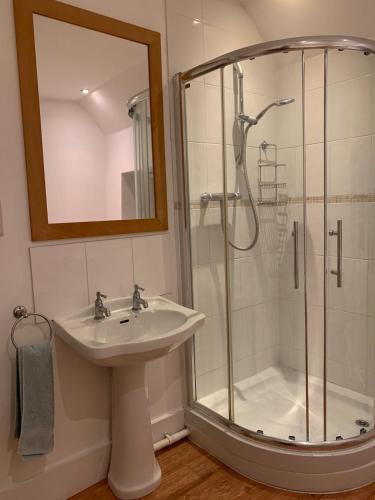 a bathroom with a shower and a sink and a mirror at Cute cob cottage in Winterborne Stickland