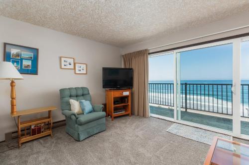 a living room with a tv and a chair and a window at Ocean Terrace Condominiums in Lincoln City