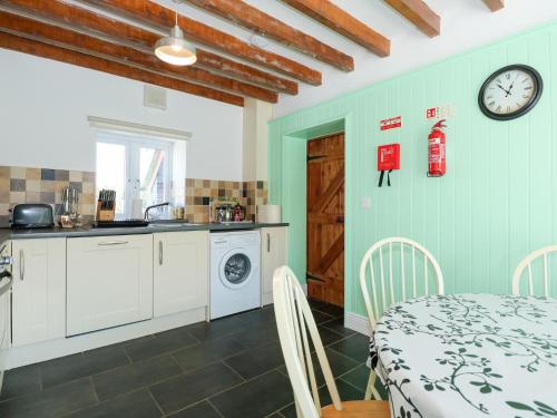 a kitchen and dining room with a table and a clock at Hafod in Llanllyfni