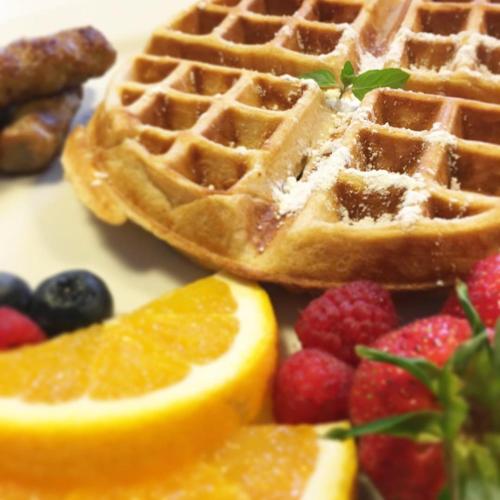 a plate with waffles and fruit on it at The New Victorian Mansion Bed & Breakfast in Saint Paul