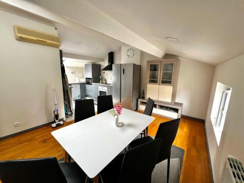 une salle à manger et une cuisine avec une table et des chaises blanches dans l'établissement Appartement T3 à Trappes, à Trappes