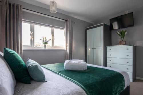 a bedroom with a green and white bed with a window at Clicketts - 3-Bedroom, Full Entire House, Sleeps 6 guests, Free wifi, Street Parking, Smart TV, Basildon, Essex London in Basildon