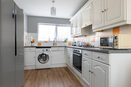 a kitchen with white cabinets and a washing machine at Clicketts - 3-Bedroom, Full Entire House, Sleeps 6 guests, Free wifi, Street Parking, Smart TV, Basildon, Essex London in Basildon