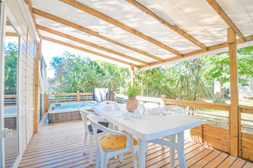 une table et des chaises blanches sur une terrasse en bois dans l'établissement Camping Merendella, à San-Nicolao
