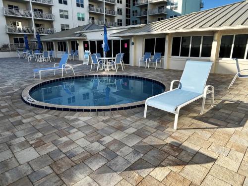 a pool with chairs and tables in a courtyard at Scenic 2br Beachfront Condo Retreat Nsb Fl in New Smyrna Beach