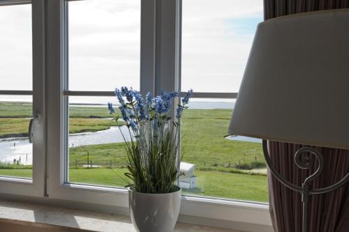 a vase with flowers in a window with a lamp at Anker's Hörn - Hotel & Restaurant auf der Hallig Langeness in Langeneß
