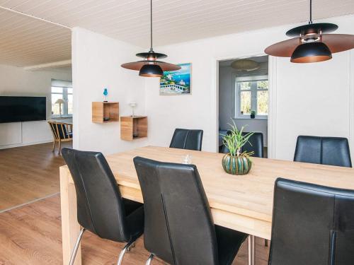 a dining room with a wooden table and black chairs at 4 star holiday home in Løkken in Løgsted