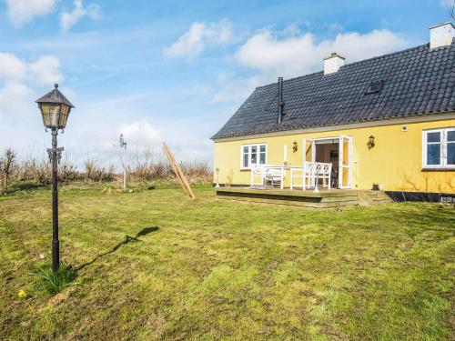 a yellow house with a porch and a street light at 4 star holiday home in Løkken in Løgsted