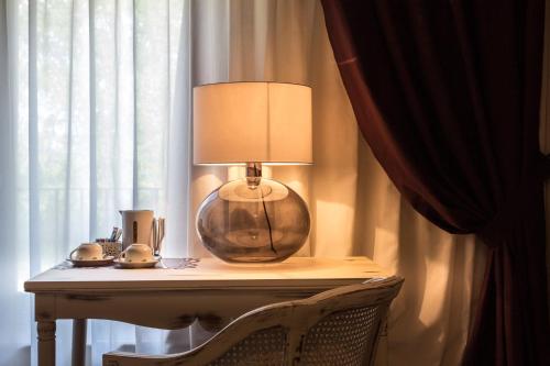 a table with a lamp and a chair next to a window at La Maison De Vì in Carpaneto Piacentino