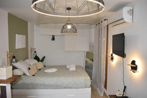 - une chambre avec un lit doté d'oreillers blancs et une télévision dans l'établissement Home lysea, à Marseille