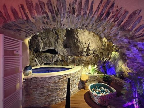 a bathroom with a stone wall and a tub at Spa Troglodyte avec Cour, à 20m des Plages, LoveRoom avec Jacuzzi ''Le Ginkgo'' in Collioure