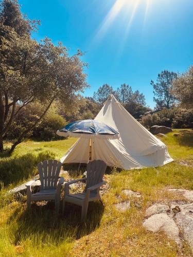two chairs and an umbrella in front of a tent at Rocky Ridge Cabin Yosemite in Coarsegold