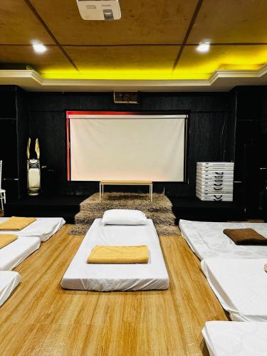 a room with a projection screen and white mattresses at HOST HOMES near AIRPORT BETA BAYVIEW in Burayan