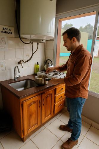 a man standing in a kitchen preparing food at Terralta Mini Cabañas y Camping in Las Compuertas