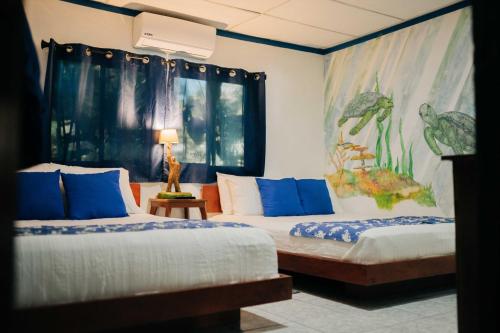 a bedroom with two beds and a painting on the wall at Olas Permanentes El Zonte in El Zonte