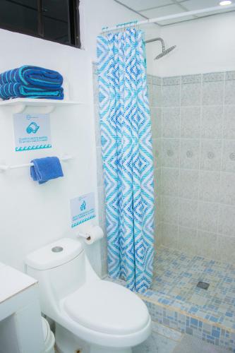 a bathroom with a toilet and a shower curtain at Olas Permanentes El Zonte in El Zonte