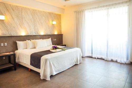 a hotel room with a large bed and a large window at Aspira Hotel Playa del Carmen in Playa del Carmen