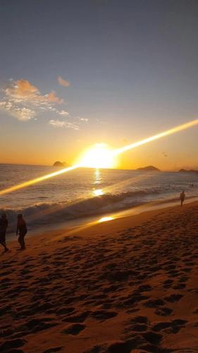 a group of people walking on the beach at sunset at "Refúgio Lima" in São Sebastião