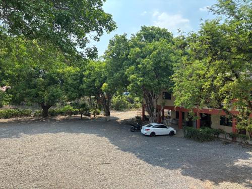a car parked in front of a house with trees at Hotel Rio Mar in Puntarenas