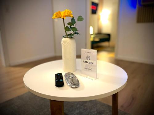 a table with a vase and a remote control on it at ZOVA - Superior Apartment - near A3 in Willroth