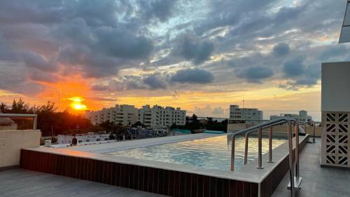 a pool on the roof of a building with a sunset at La Poza Condominio in Isla Mujeres