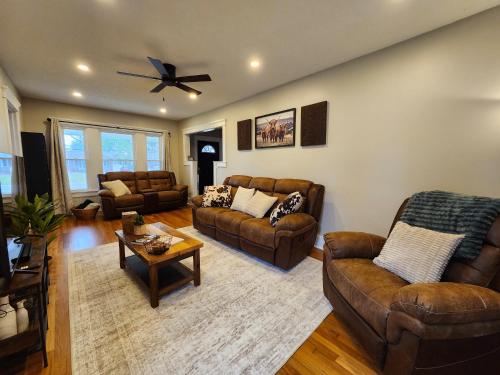 a living room with leather furniture and a ceiling fan at The Farmhouse in Elyria, OH in Elyria