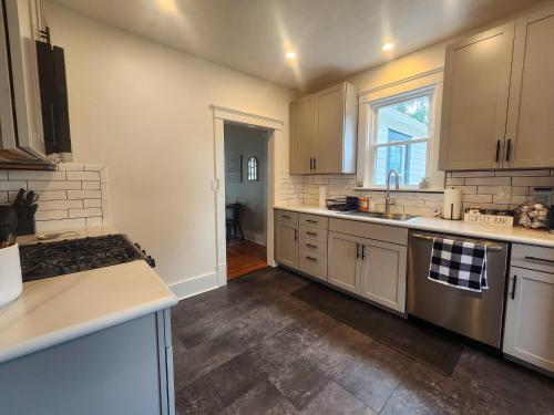 a kitchen with white cabinets and a sink and a stove at The Farmhouse in Elyria, OH in Elyria