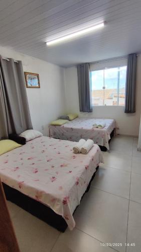 a bedroom with two beds and a window with a view at Casa Aconchegante in Marechal Deodoro